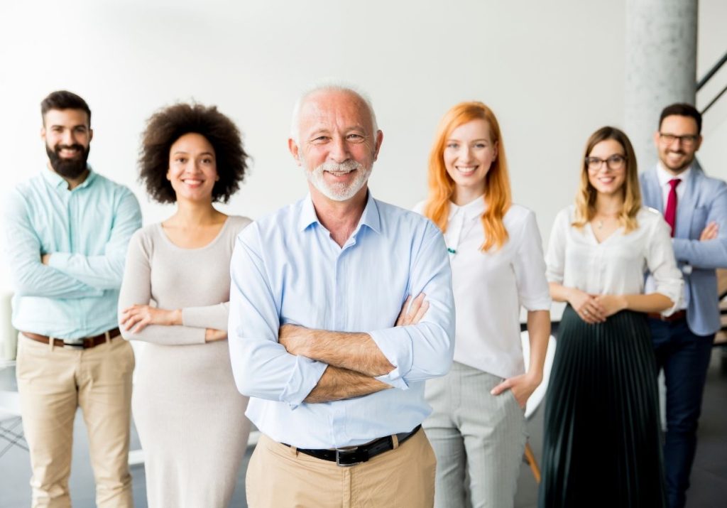 Um grupo de seis profissionais, sorrindo e posando com braços cruzados em um ambiente corporativo. Curso Introdutório de Formação e Qualificação de Dirigentes.