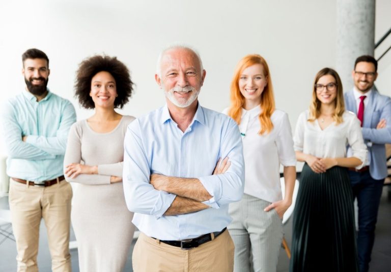 Um grupo de seis profissionais, sorrindo e posando com braços cruzados em um ambiente corporativo. Curso Introdutório de Formação e Qualificação de Dirigentes.